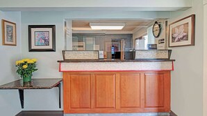 A kitchen with wooden cabinets, a granite countertop, and a vase of yellow flowers. - Super 8 by Wyndham Sacramento/Florin Rd (Sacramento)