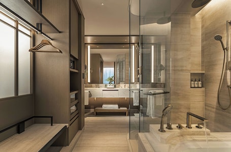 A modern bathroom with a glass shower enclosure, a vanity with a mirror, and a bench.. Four Seasons Hotel Tokyo at Marunouchi