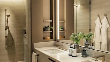 Une salle de bain moderne dotée d’une douche à parois de verre, de deux vasques et d’un grand miroir qui reflète un porte-serviettes.