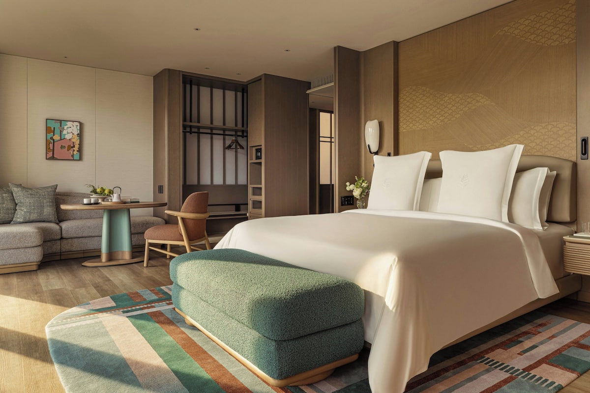 Une chambre d’hôtel moderne équipée d’un lit, d’un coin salon et d’une petite table.