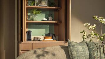 A room with a wooden cabinet, a sofa, and a table with books and a vase.