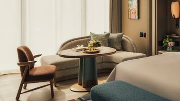 A modern hotel room with a sofa, chair, round table, and a bed.