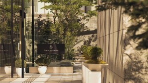 L'ingresso di un hotel con insegna, piante in vaso e facciata di un edificio moderno.