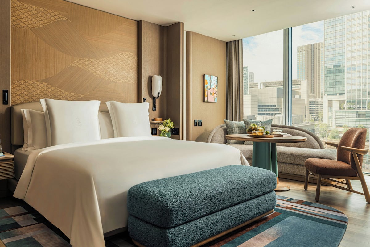 Une chambre d’hôtel avec un grand lit, une petite table, une chaise et une vue sur la ville.