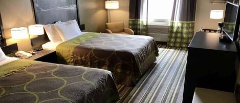 Une chambre d’hôtel avec deux lits, un bureau, une chaise, une télévision et une fenêtre avec des rideaux.