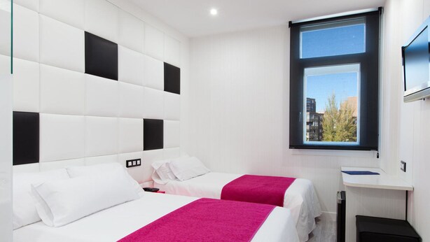 Une chambre d’hôtel avec deux lits, une grande fenêtre et un bureau.