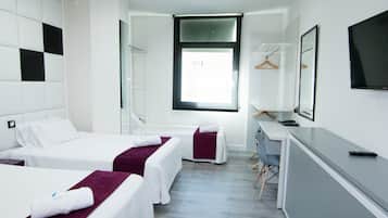 Habitación de hotel con dos camas, un escritorio, una silla, un televisor y una ventana.