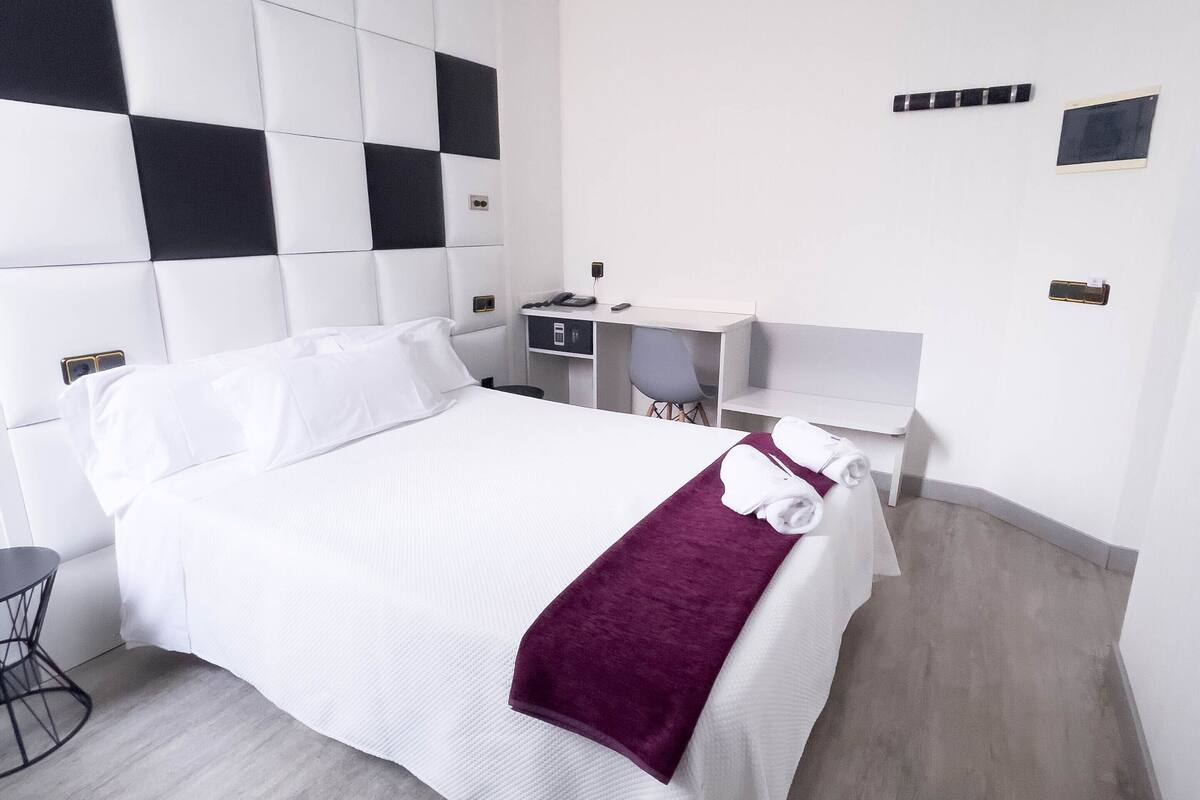 Een moderne hotelkamer met een groot bed, een bureau en een stoel.