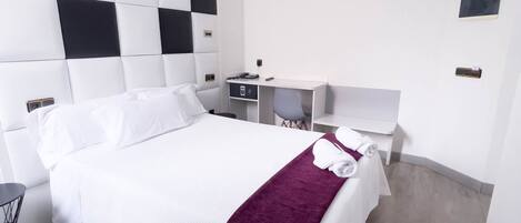 Une chambre d’hôtel moderne, dotée d’un grand lit, d’un bureau et d’une chaise.