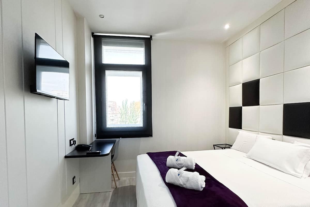 Een moderne hotelkamer met een groot bed, een bureau en een aan de muur bevestigde televisie.