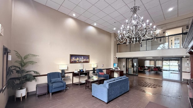 A spacious lobby with a chandelier, seating area, and a large window overlooking the interior.