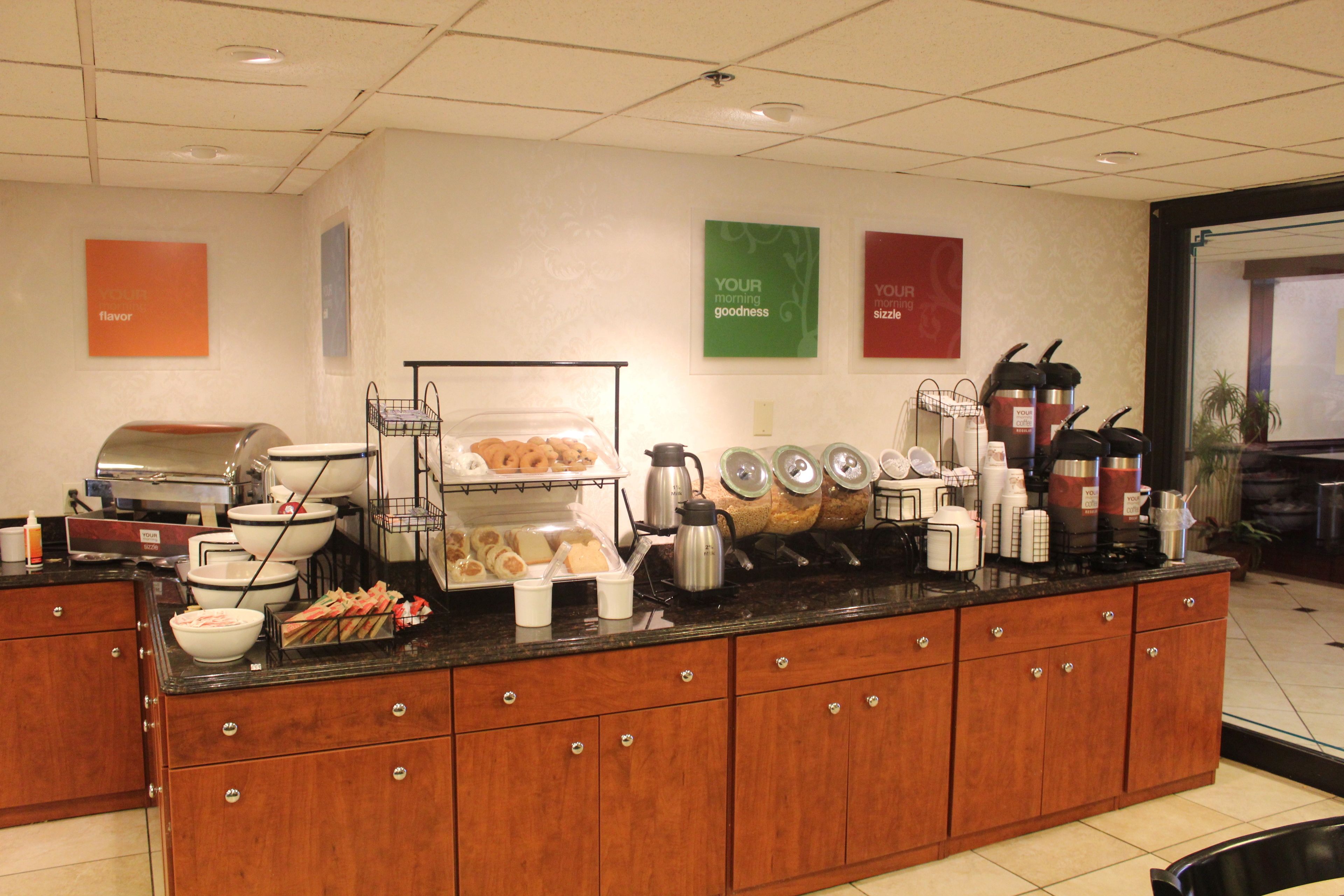 A breakfast bar with coffee makers, a toaster, and a variety of food items.