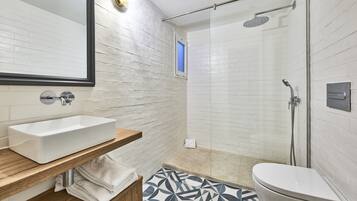 Un baño moderno con un lavamanos rectangular, un inodoro y una zona de ducha.