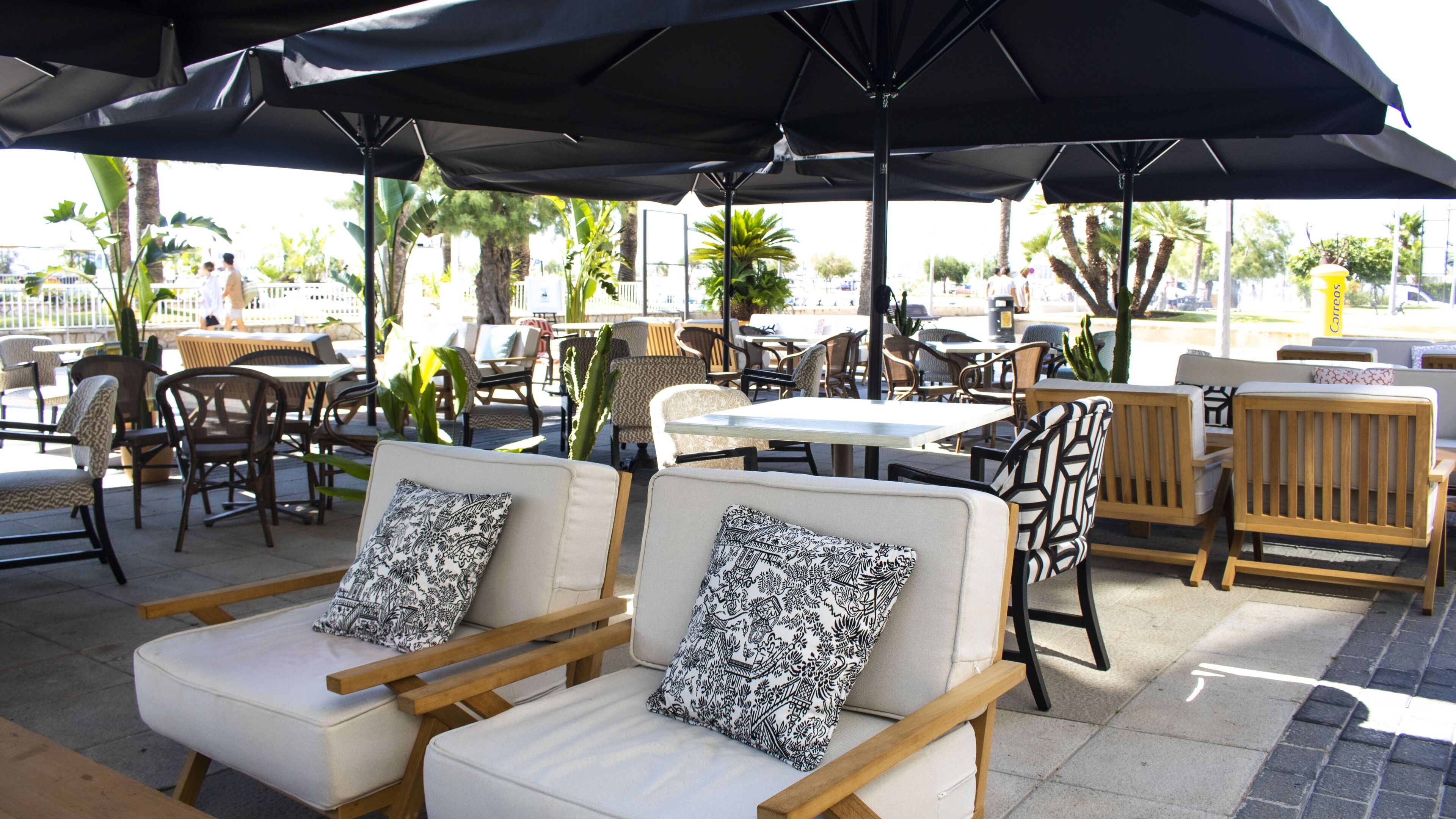 An outdoor seating area with tables and chairs, some with umbrellas.