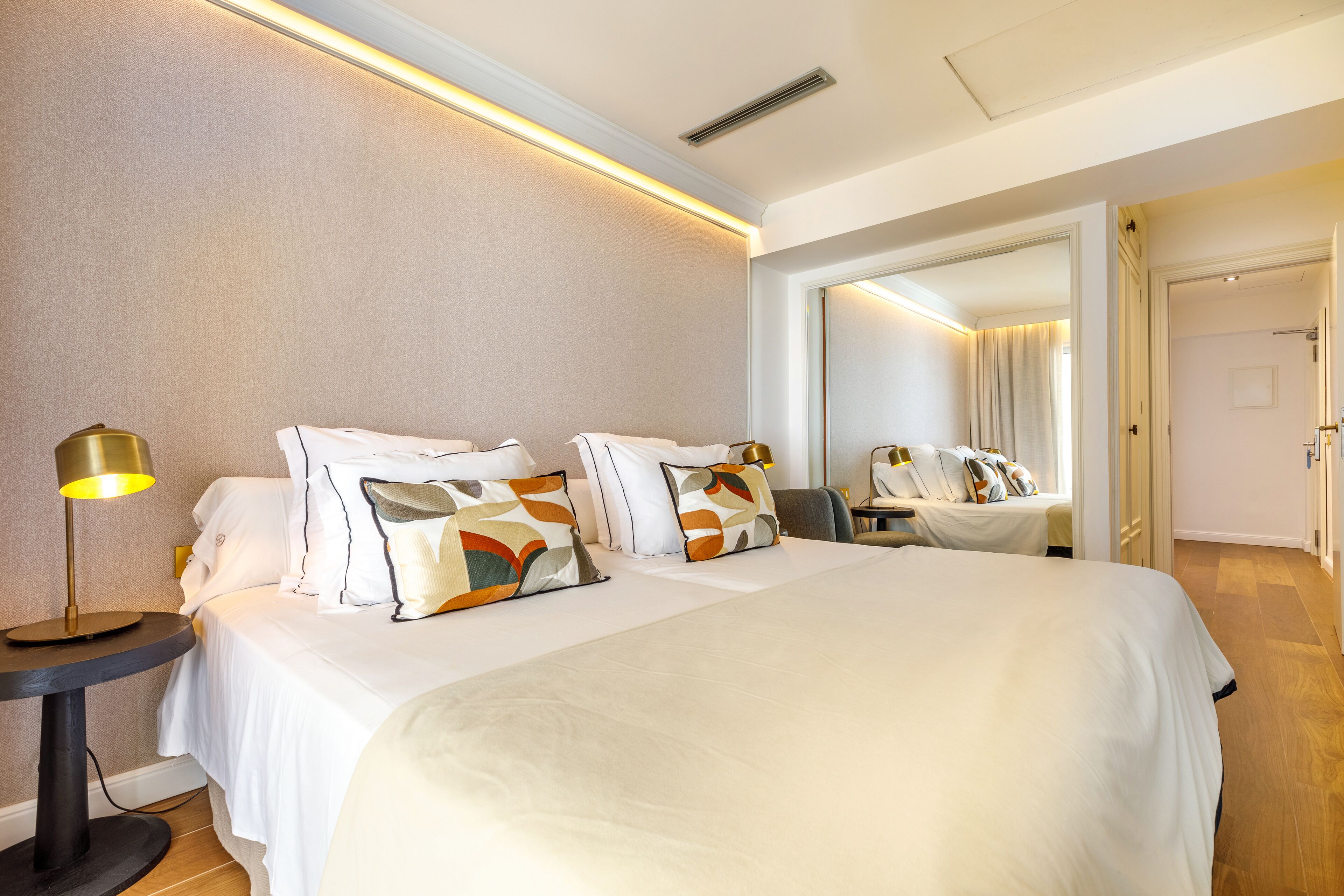Une chambre d’hôtel avec un grand lit, des tables de chevet, une lampe et un miroir.