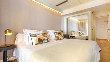 Une chambre d’hôtel avec un grand lit, des tables de chevet, une lampe et un miroir.