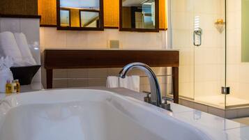 Un baño moderno con una bañera grande, un banco de madera y una cabina de ducha de vidrio.