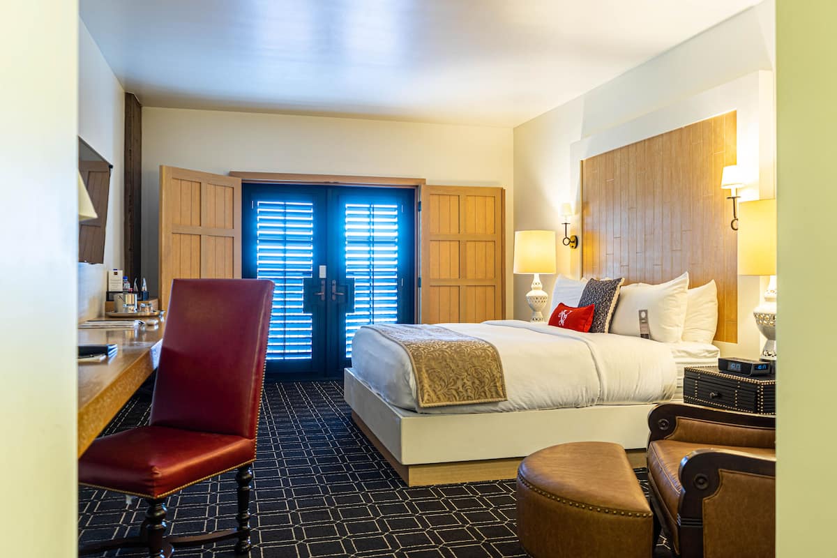 A hotel room with a bed, a desk, a chair, and a wardrobe.
