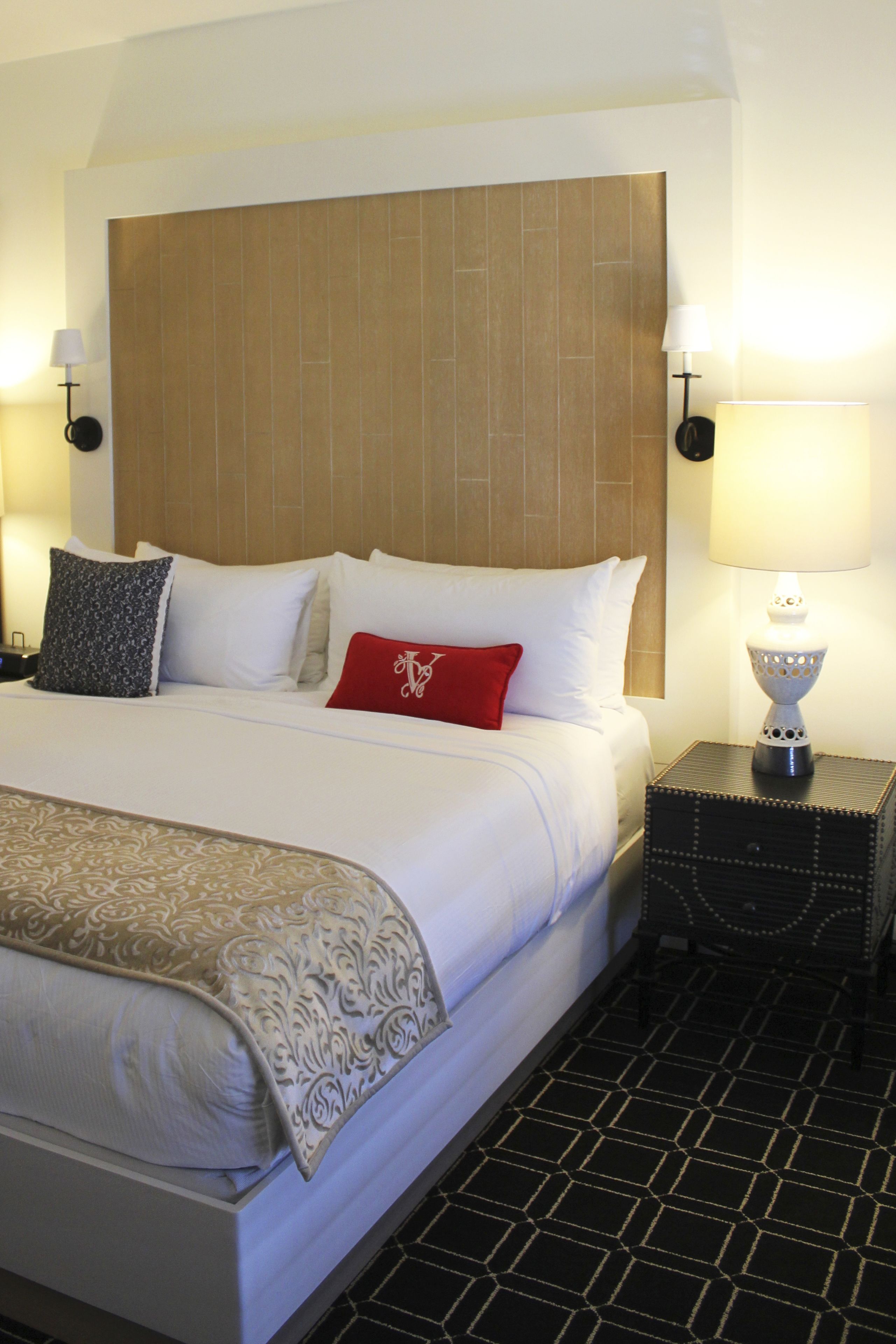 A neatly made bed with a patterned throw, a wooden headboard, and two bedside lamps.