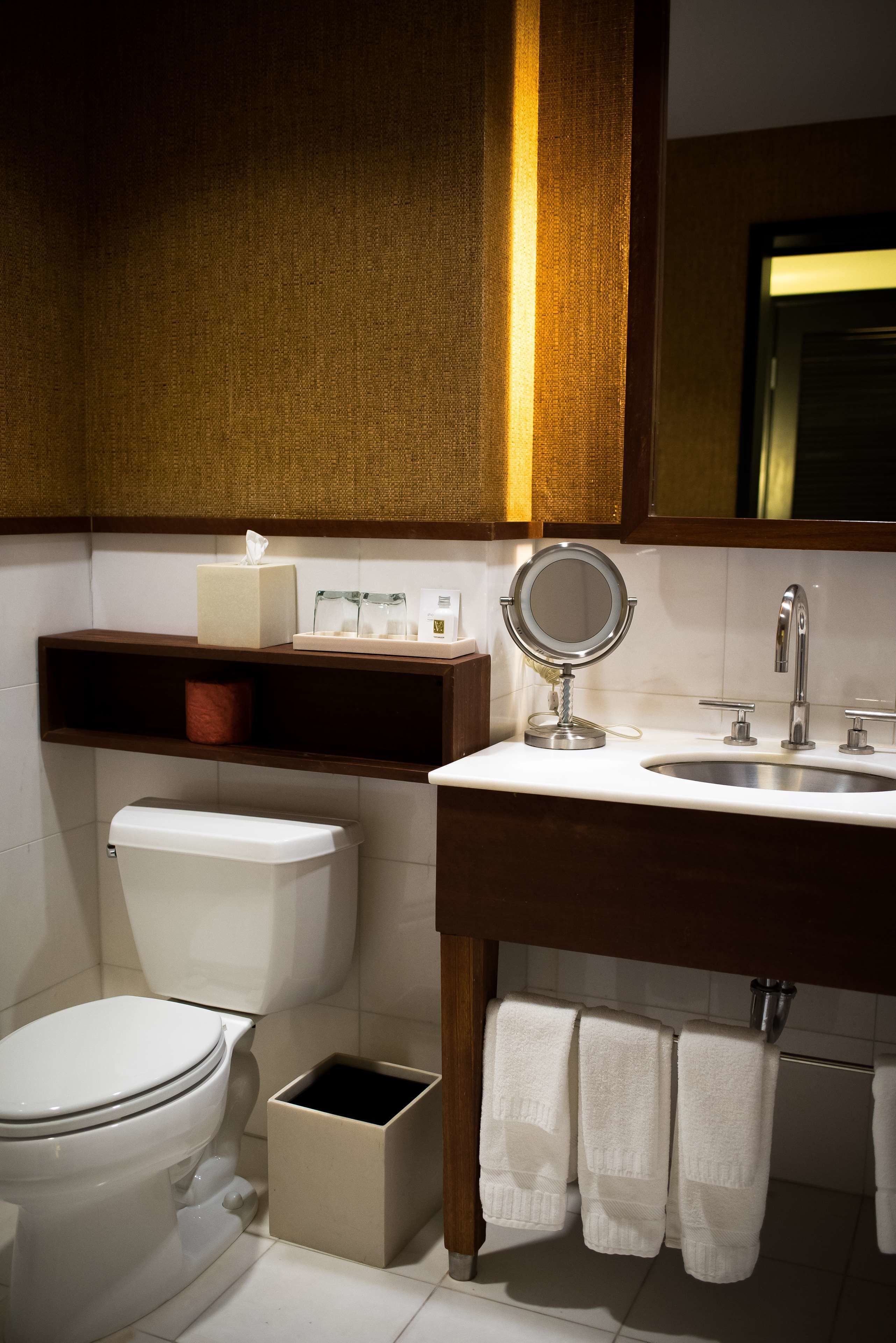 Un baño con inodoro, lavabo, espejo y toallero.