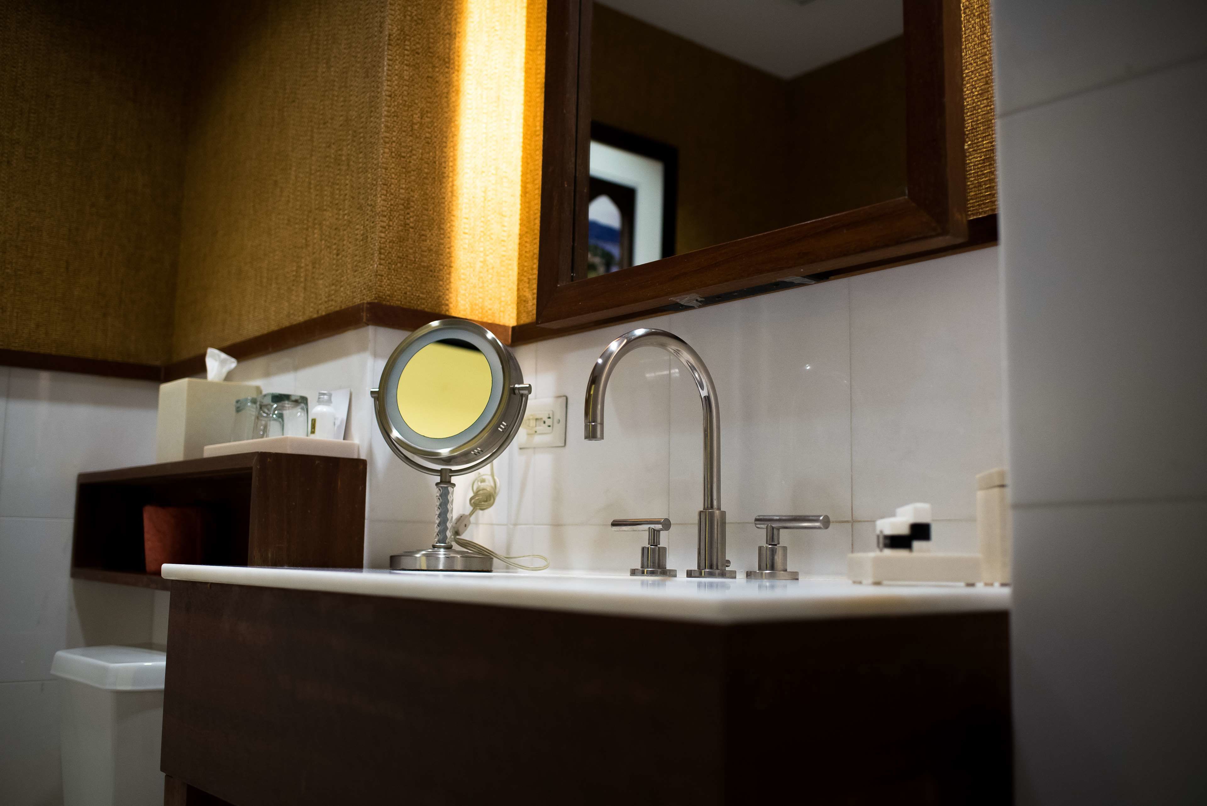 Un baño con tocador, espejo, lavabo y perchero para toallas.