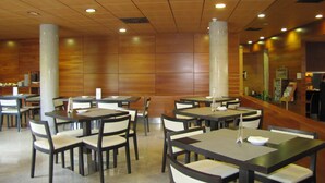 A modern restaurant interior with wooden panel walls, multiple tables and chairs, and recessed ceiling lights. - Eco Via Lusitana (Madrid)