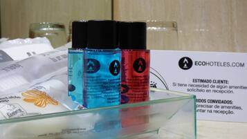 A glass display case with three bottles of liquid soap, a sign with hotel information, and a partially visible white package.