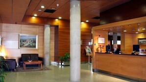 A hotel lobby with a reception desk, seating area, and a large painting on the wall. - Eco Via Lusitana (Madrid)