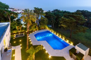 Una piscina con el letrero 'Lidohotel', rodeada de senderos bien iluminados y palmeras.