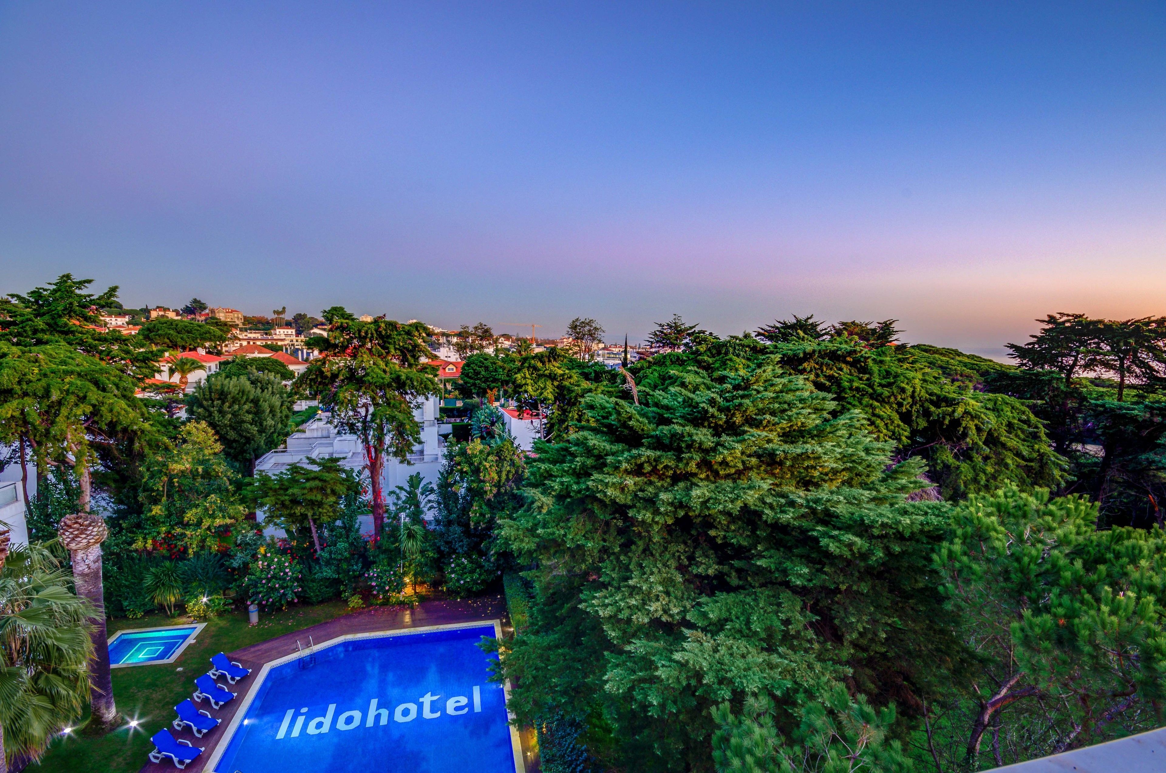 A hotel with a pool area surrounded by lush greenery and trees.