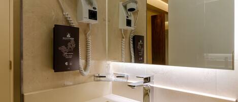 A modern bathroom with a large mirror, a built-in hair dryer, and a bottle of Algotherm liquid soap.
