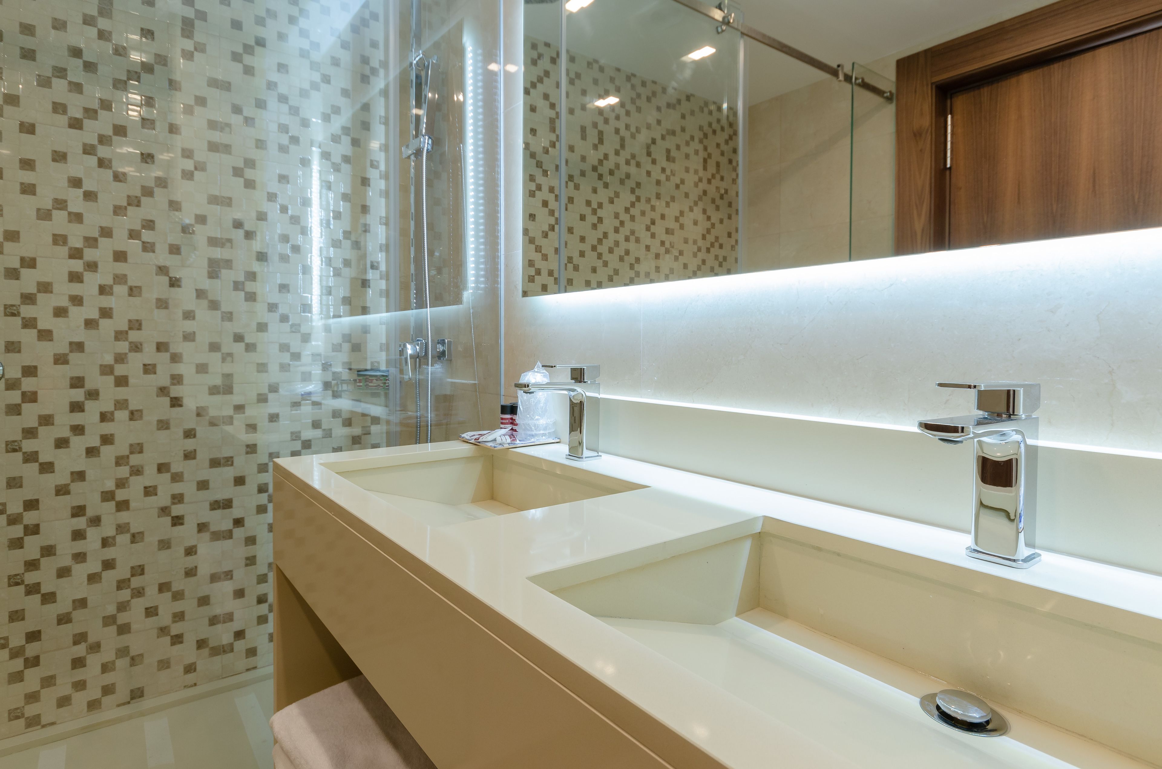 Un baño moderno con dos lavamanos, cabina de ducha de vidrio y un espejo grande.