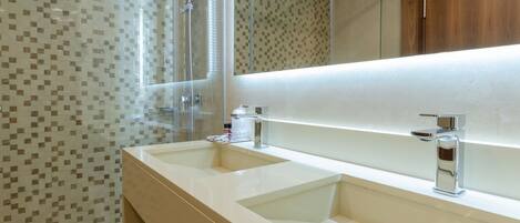 Un baño moderno con dos lavamanos, cabina de ducha de vidrio y un espejo grande.