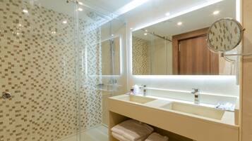 A modern bathroom with a glass-enclosed shower, a large mirror, and two sinks.