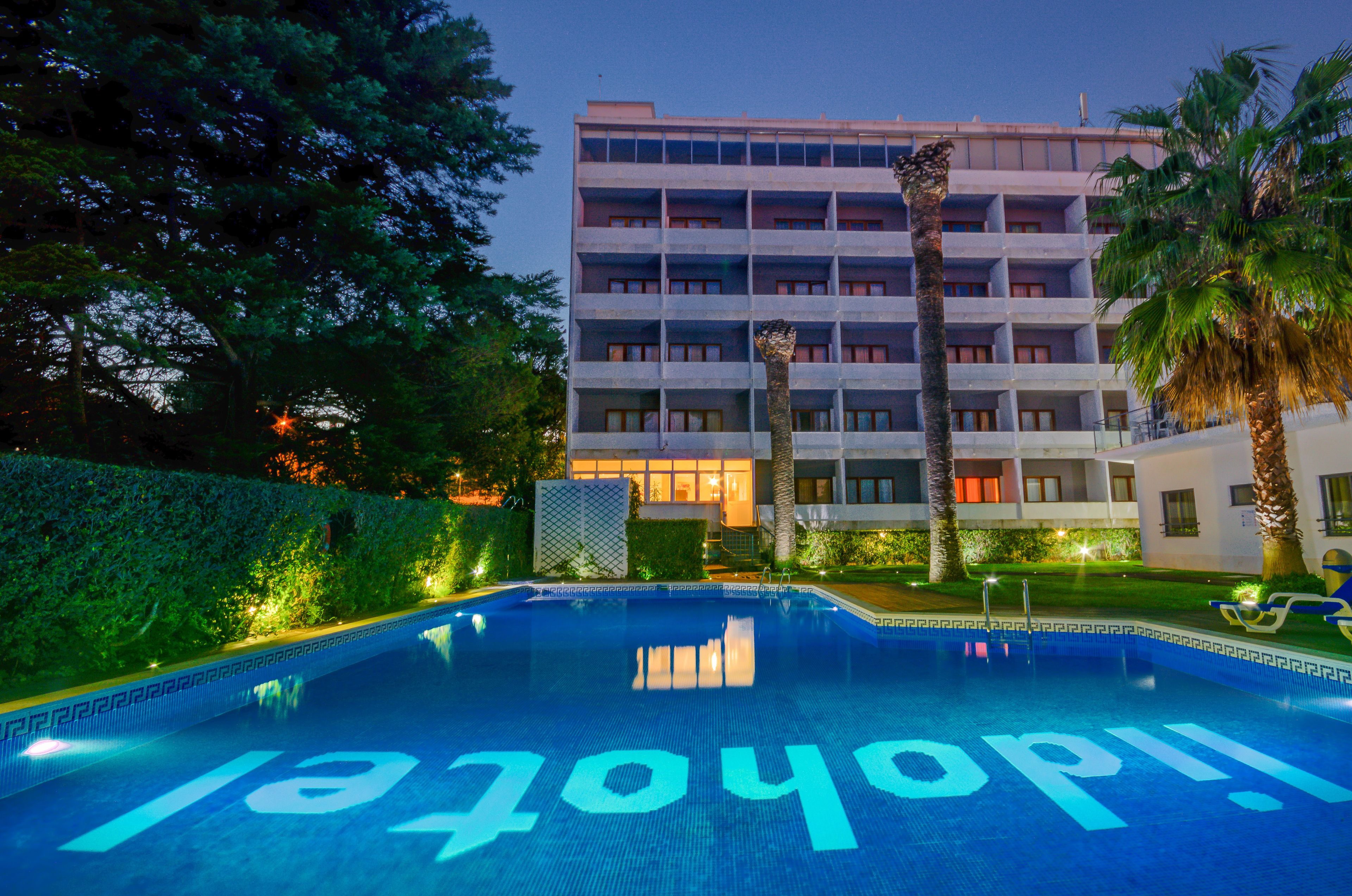 A hotel with a swimming pool, a multi-story building, and palm trees.