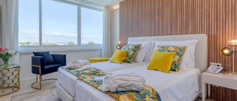 A modern hotel room with a large bed, a desk, and a view of the city.