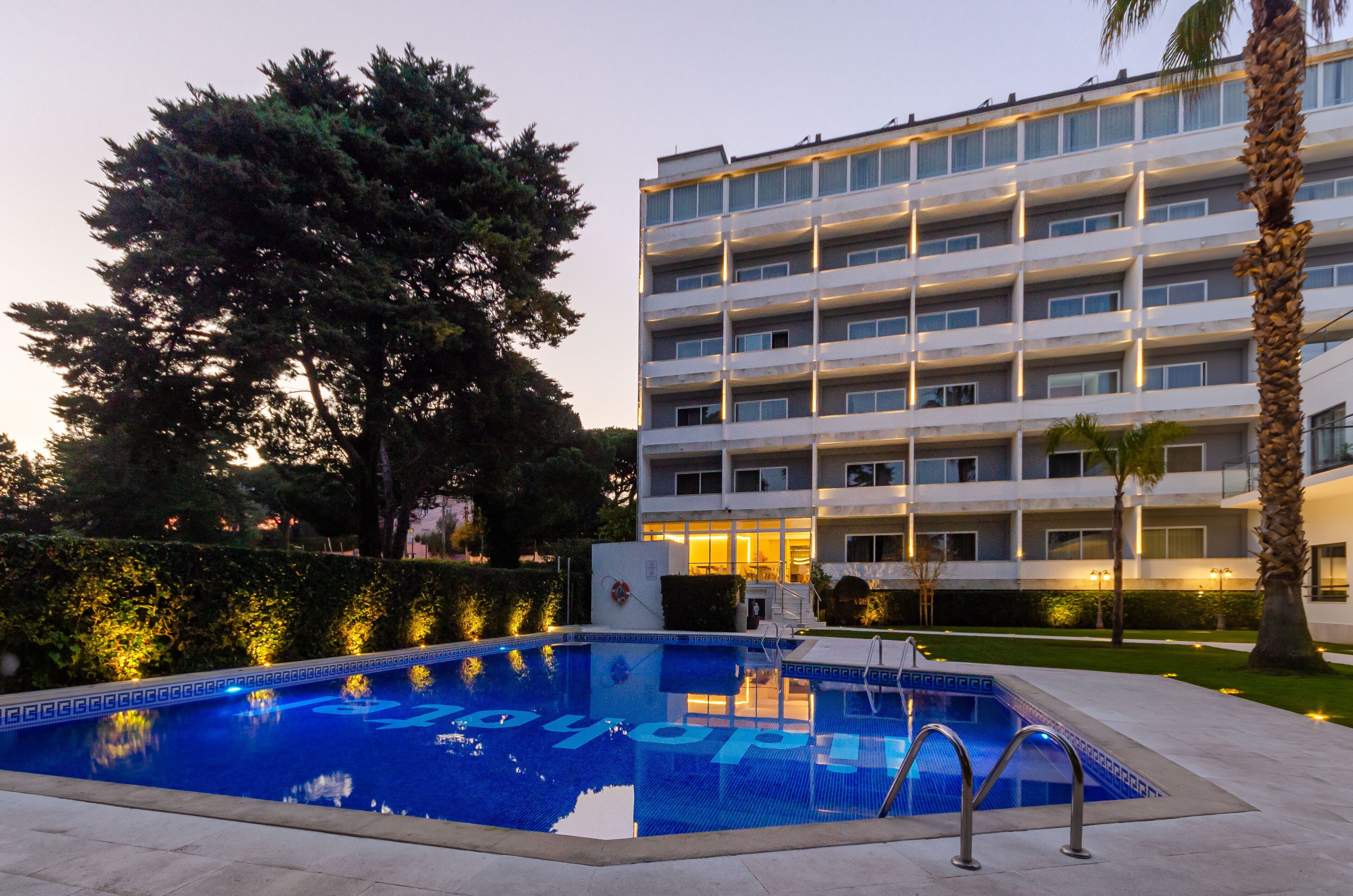 Une piscine à l’eau d’un bleu limpide et, en arrière-plan, un bâtiment doté de nombreux balcons.