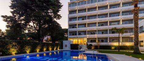 Une piscine à l’eau d’un bleu limpide et, en arrière-plan, un bâtiment doté de nombreux balcons.