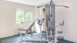 A gym with a weight machine, a bench, and a wall-mounted rack. - Sturbridge Hotel (Sturbridge)