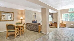 A spacious living area with a wooden dining set, a sofa, and a fireplace. - Sturbridge Hotel (Sturbridge)