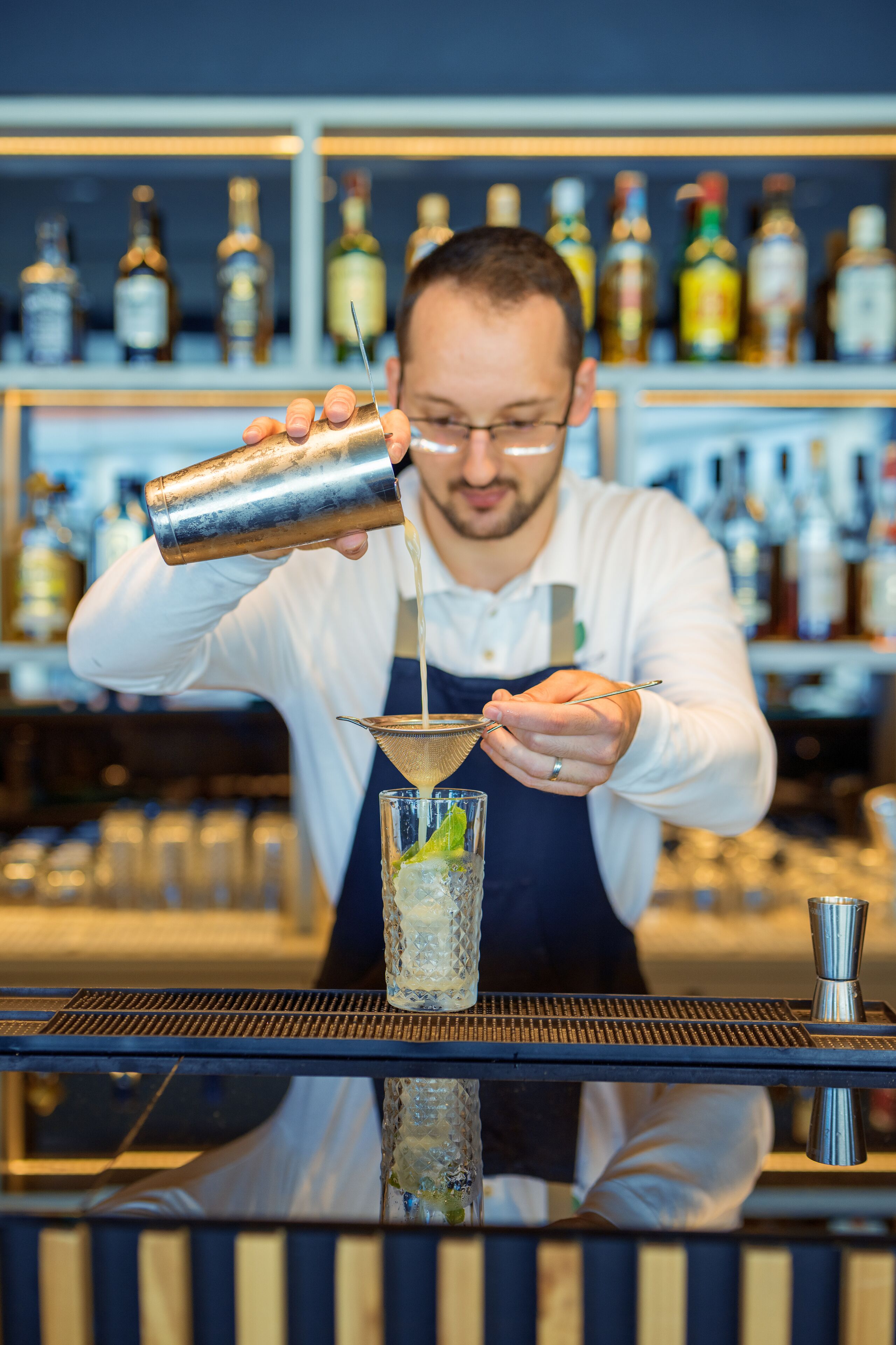 A bartender pouring a drink into a glass.