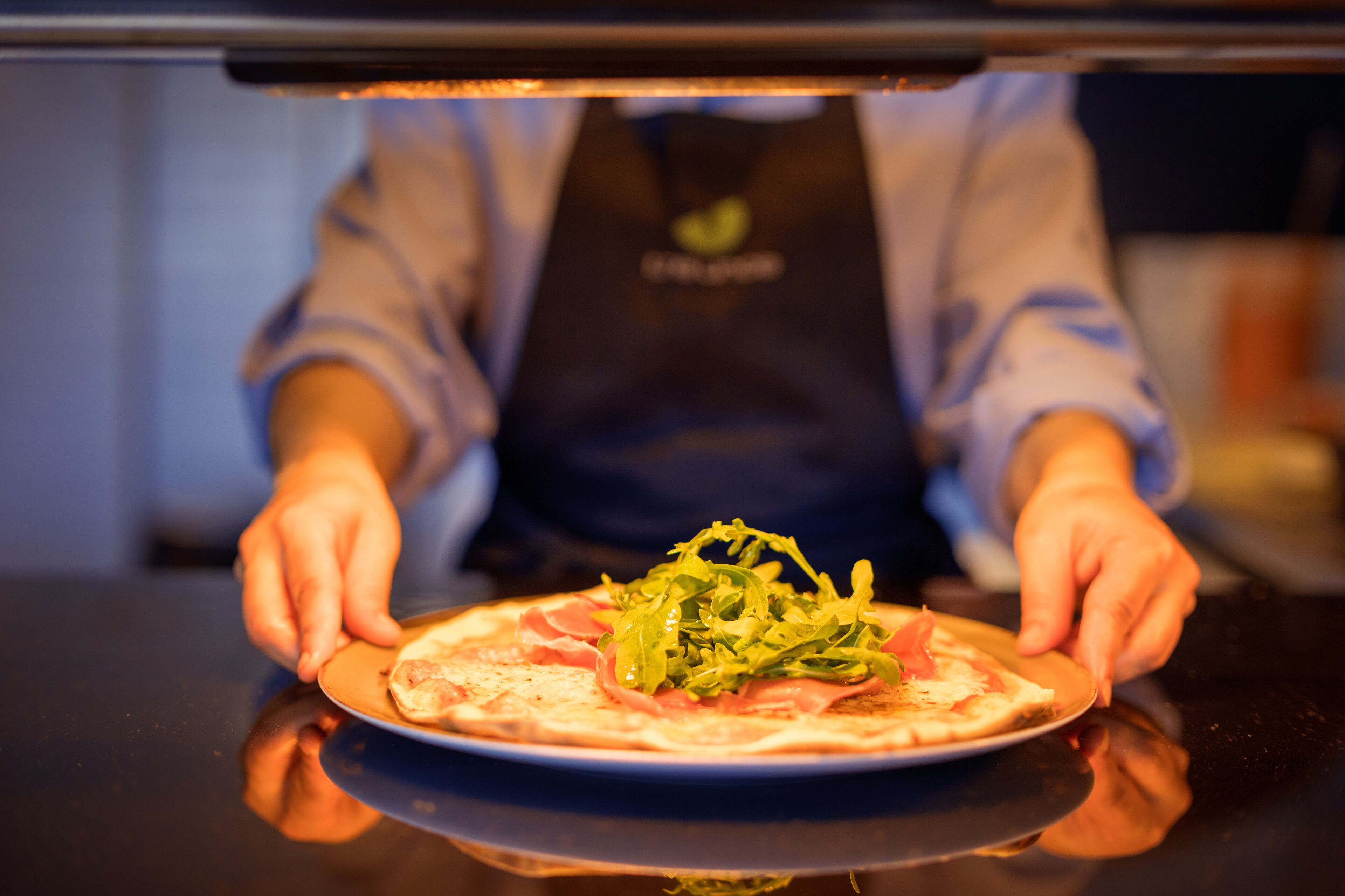 A person placing a pizza on a plate inside an oven.