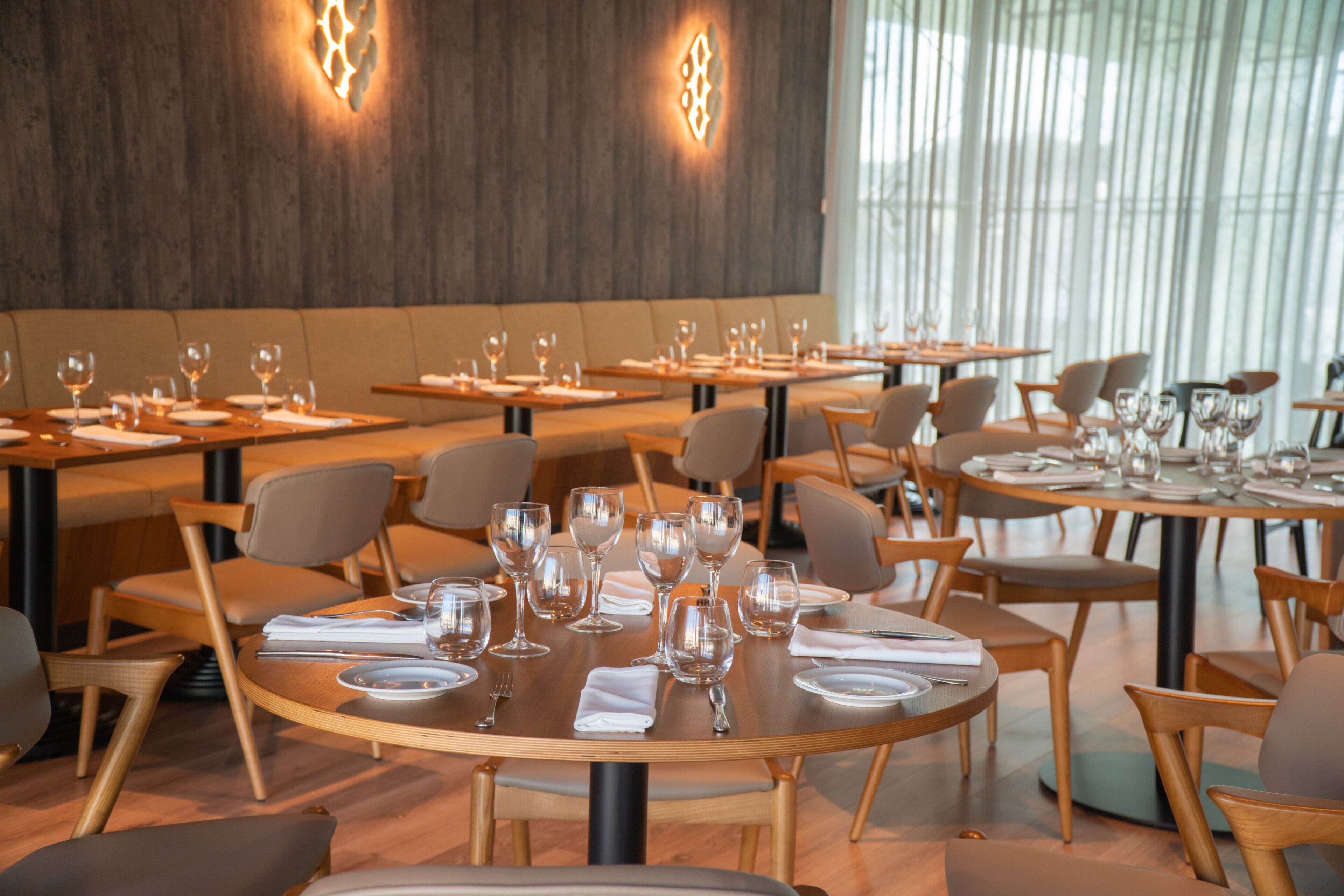 Ein modernes Restaurant mit runden Tischen und Stühlen, das großzügig gestaltet ist.