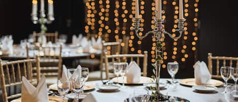 A well-set dining table with candles, glasses, and folded napkins.