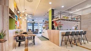A modern bar area with a counter, bar stools, and shelves with bottles. - Holiday Inn Brussels Schuman by IHG (Brussels)