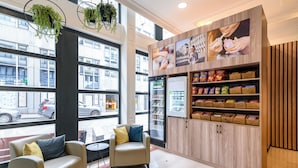 A modern interior with seating, a refrigerator, and snack shelves.