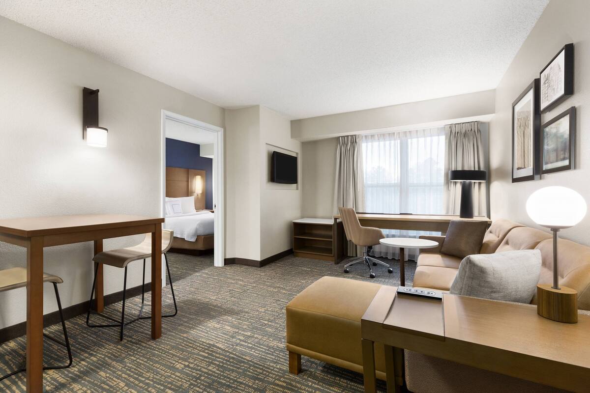 A hotel room with a bed, desk, chair, sofa, and a TV.