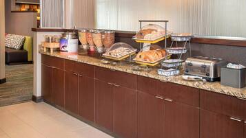 Un mostrador de desayuno de hotel con diversos alimentos, un tostador y una máquina de café.