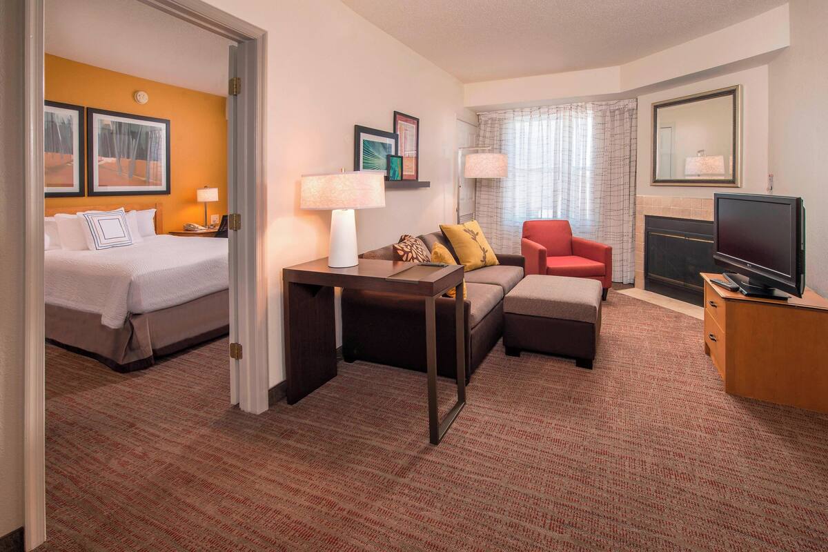 Quarto de hotel com cama, sofá, televisão e lareira.