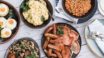 Variedad de platos que incluyen huevos, puré de papas, frijoles, salchichas y champiñones.